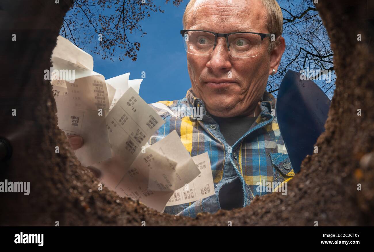 Ein Mann will seine Quittungen in einem Erdloch loswerden Stockfoto