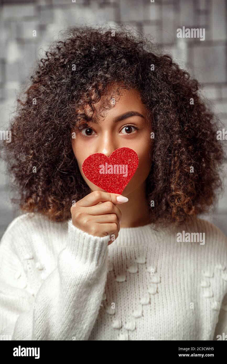 Nahaufnahme Porträt eines jungen rothaarigen afroamerikanischen Mädchen in einem weißen Pullover mit einem Papier h Stockfoto