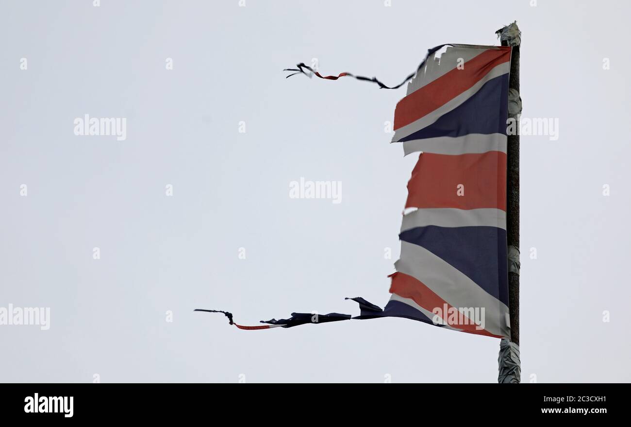 Union Jack, britische Flagge, zerfetzelt, gerissen, fliegen und flattern auf einem grauen Pfosten mit grauem Himmel könnte eine Katastrophe wie Krieg, Sturm oder Brexit illustrieren. Stockfoto