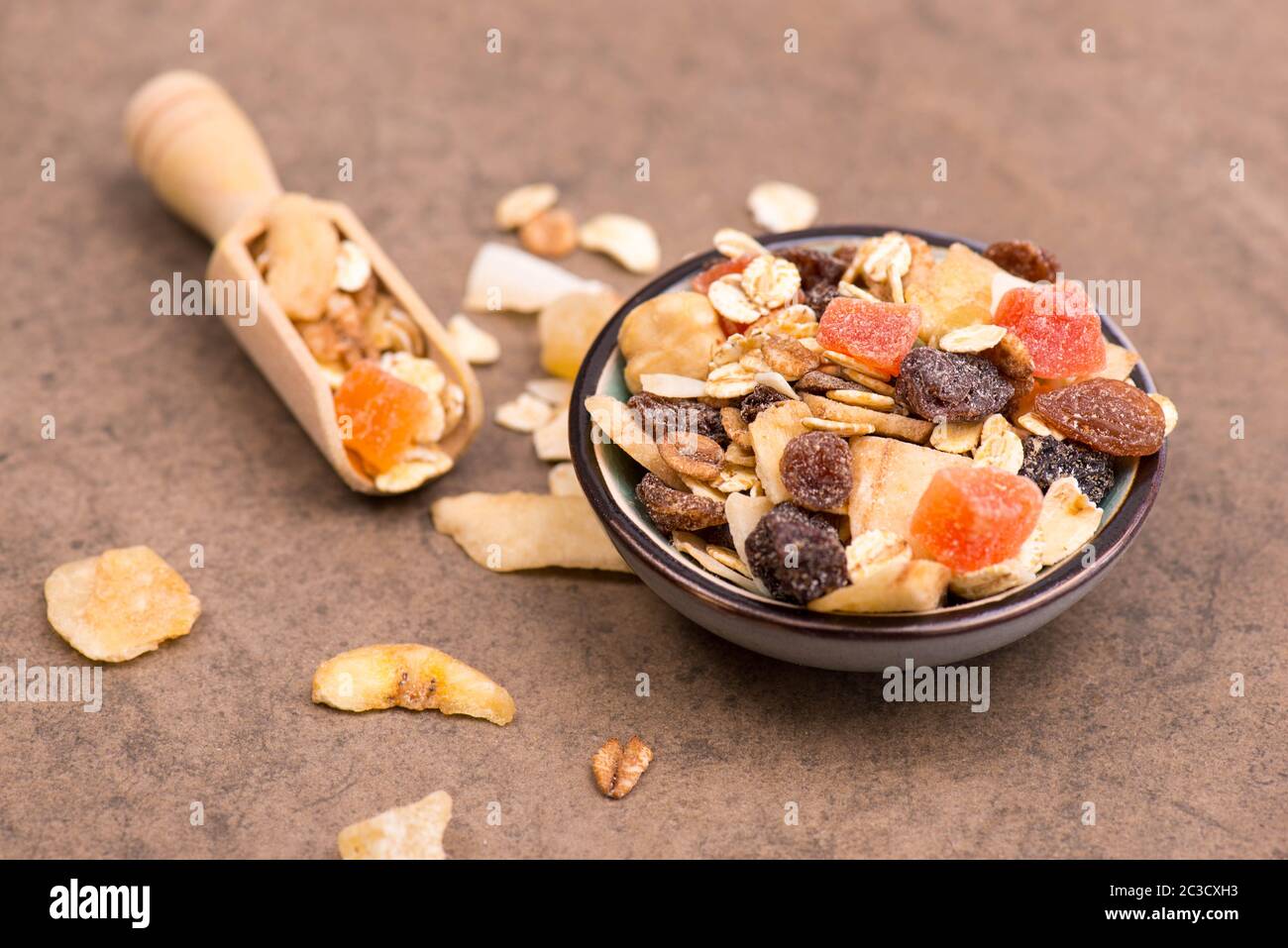 Müsli mit Getreide und Früchten auf braunem Strukturhintergrund Stockfoto