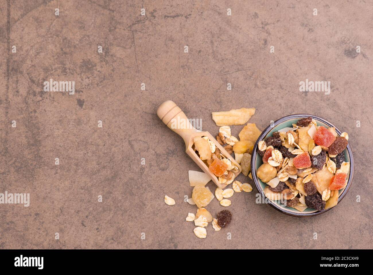 Müsli mit Getreide und Früchten auf braunem Strukturhintergrund Stockfoto