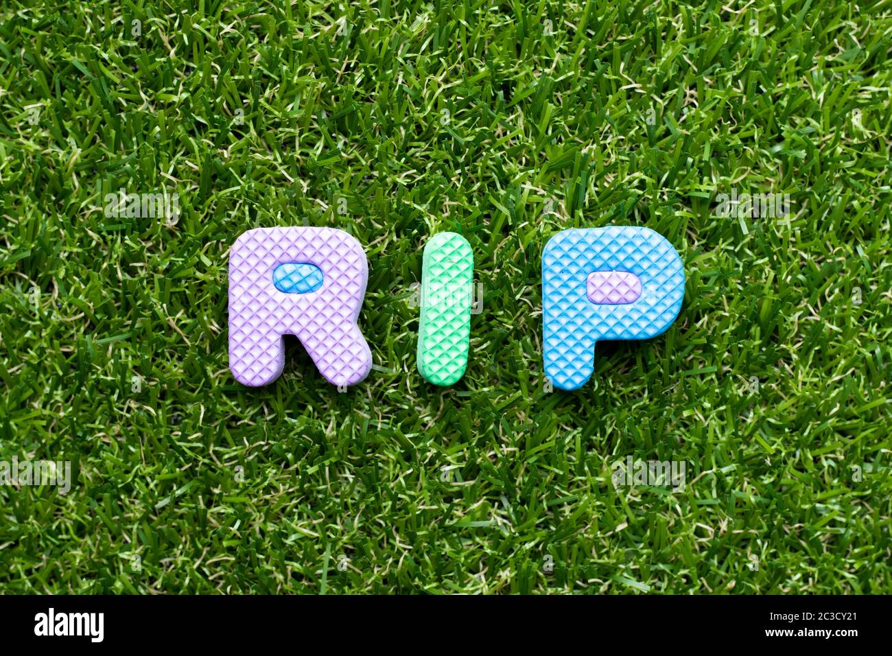 Spielzeug Schaumstoff Buchstaben in Wort RIP (Abkürzung für Ruhe in Frieden) auf grünem Gras Hintergrund Stockfoto