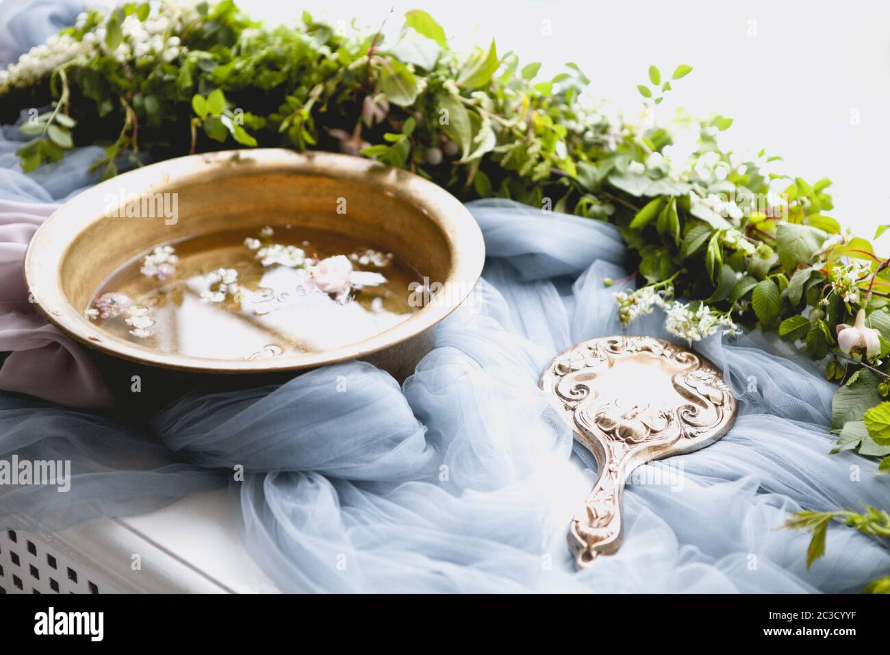 Fancy Handspiegel und Schüssel Wasser zwischen Blättern und Blumen für die Hautpflege Verfahren vorbereitet Stockfoto