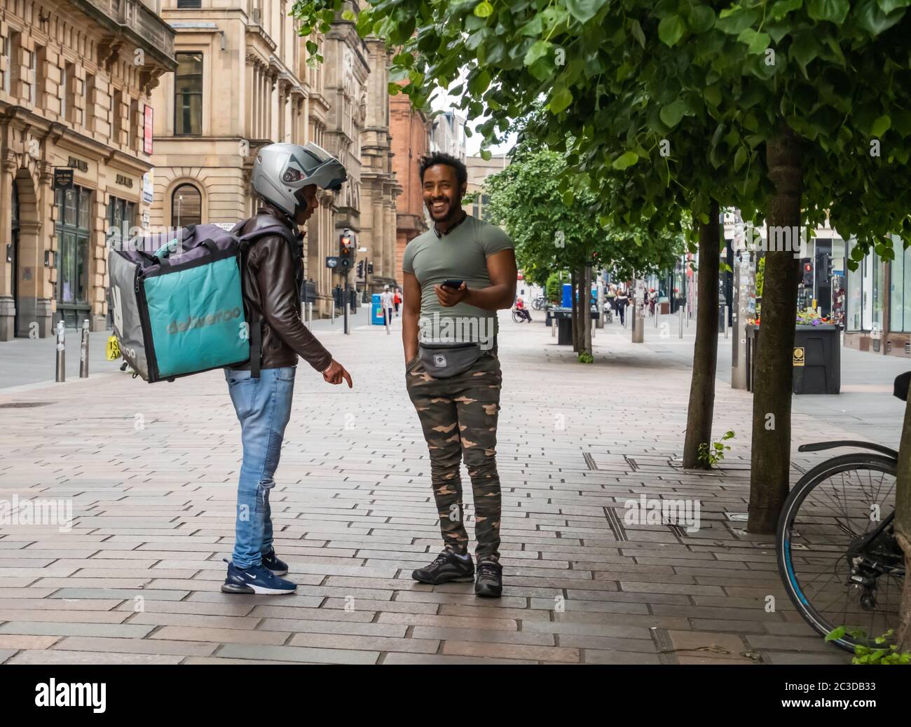 Glasgow, Schottland, Großbritannien. Juni 2020. Deliveroo Lieferung Radfahrer mit einem Chat auf Buchanan Street. Die schottische Regierung kündigte am 18. Juni eine weitere Lockerung der Coronavirus-Sperrregeln mit dem Beginn der zweiten Phase eines vierteiligen Übergangs aus der Sperrzeit an. Kredit: Skully/Alamy Live Nachrichten Stockfoto