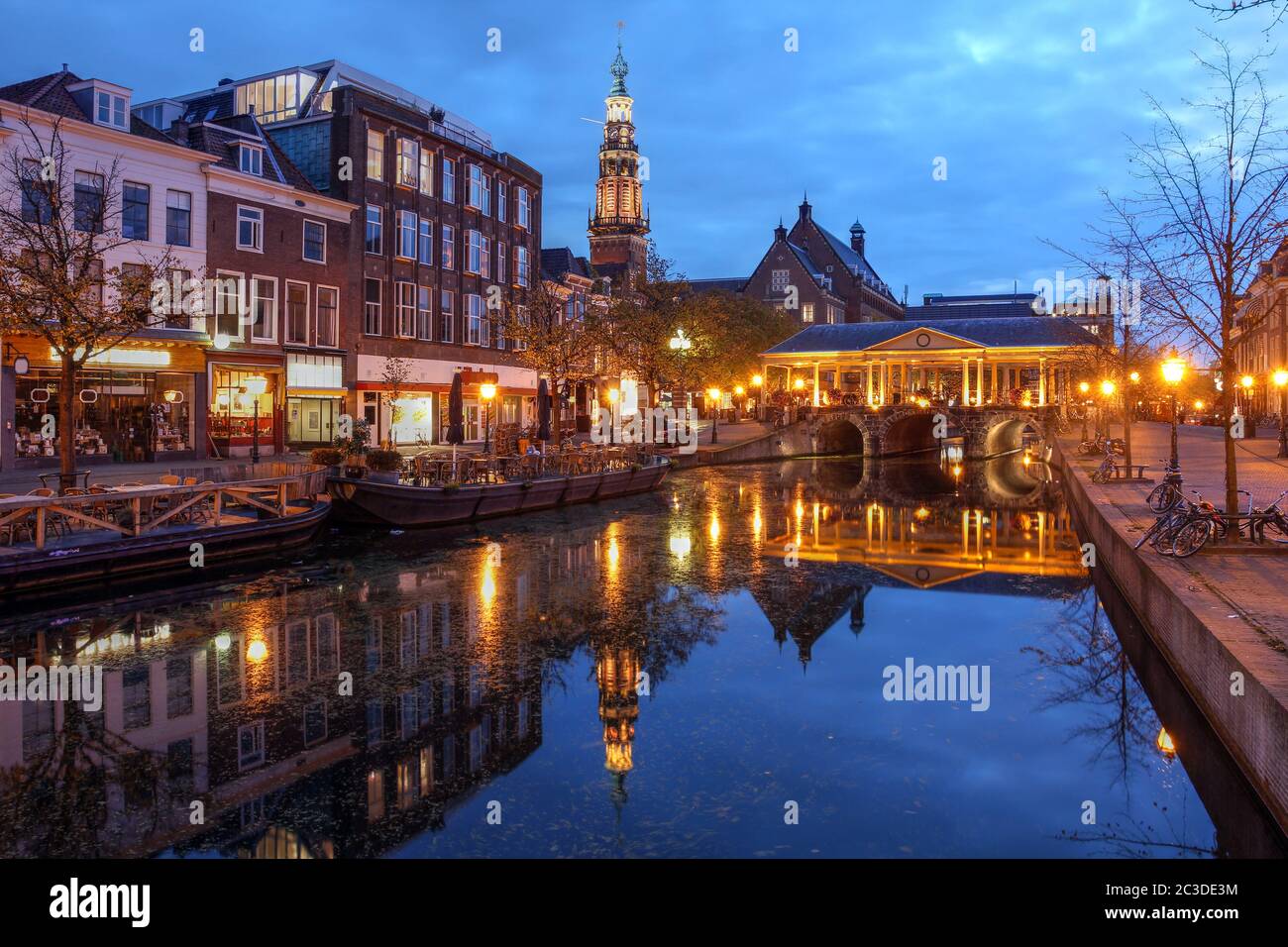 Nachtszene in Leiden, Niederlande mit der Korenbeursbrücke und dem Rathaus (Stadhuis). Stockfoto
