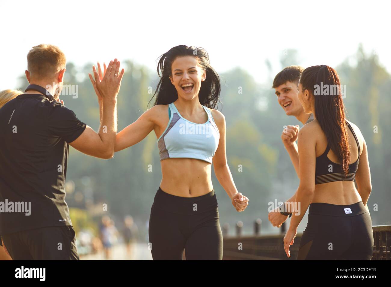 Die Läuferin macht Spaß mit einer Gruppe von Freunden in einem Park Stockfoto