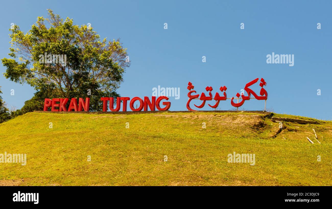 Tutong, Brunei: Schild 'Pekan Township' in malaiischer und arabischer Sprache auf einem Bergrücken am Ortseingang Stockfoto