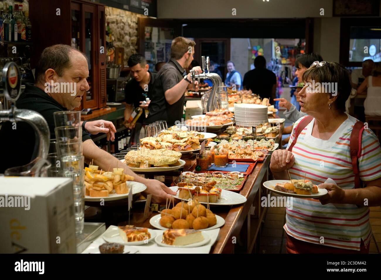 Barkeeper und Kunde in einem Pincho Bar Restaurant mit verschiedenen Pinchos Typen an der Theke.San Sebastian.Baskenland.Spanien Stockfoto