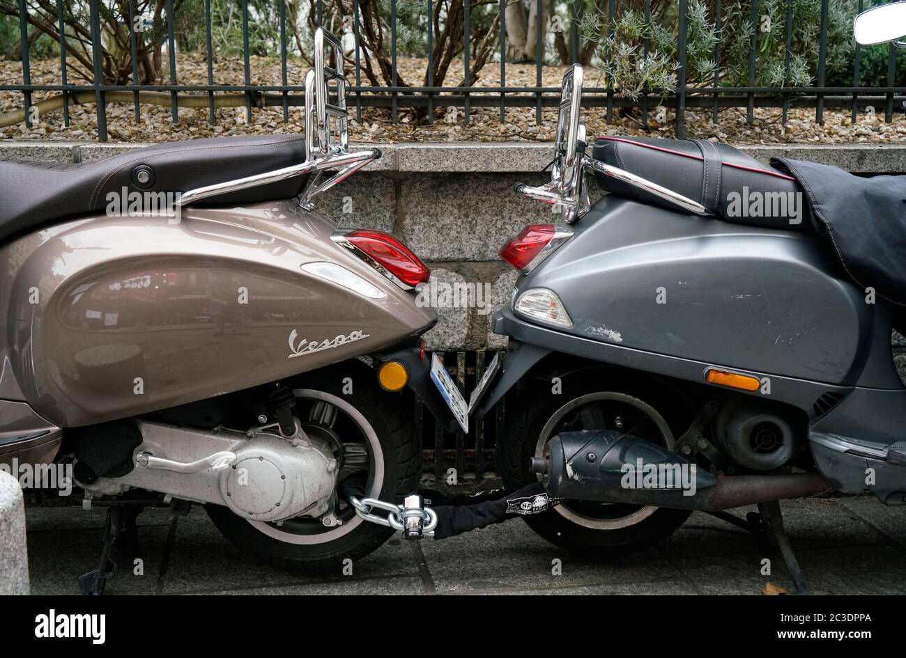 Zwei Vespa Motorroller, die zusammen auf dem Bürgersteig der Stadt einsperren.Paris.Frankreich Stockfoto