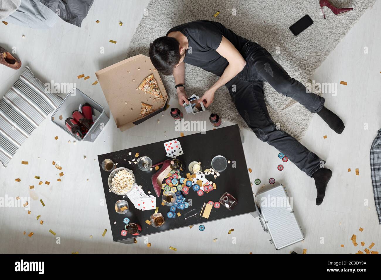 Oben Blick auf jungen Mann auf dem Boden liegen und beobachten Party-Fotos nach der Party Stockfoto