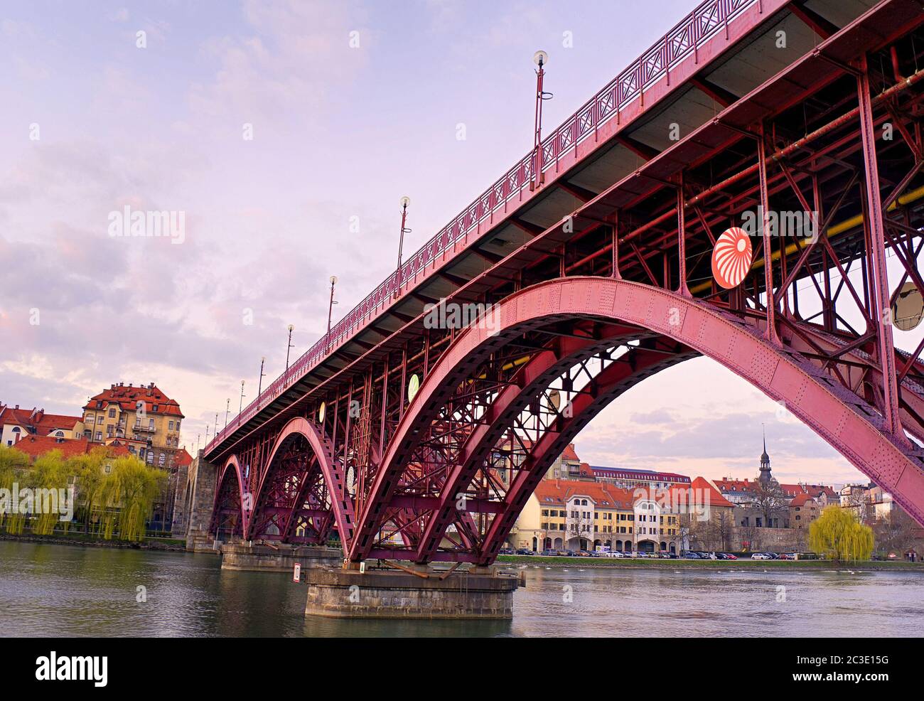 Maribor, Slowenien, Europa. Hauptbrücke (Glavni most, Stari most) über die Drau. Beliebte Flussufer Fastenzeit im Hintergrund. Sonnenuntergang und Abend. Stockfoto