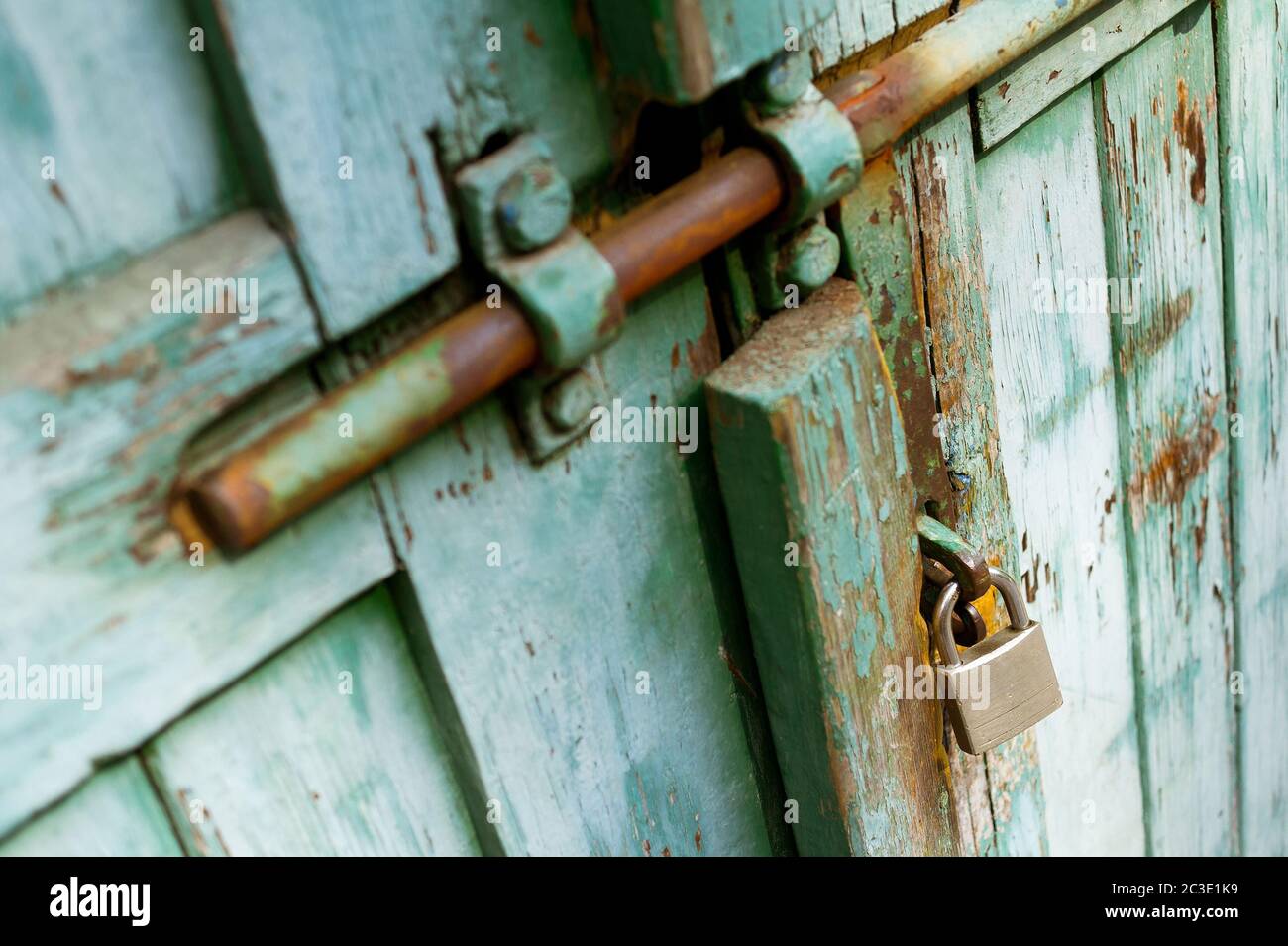 Alte rustikale Tür mit neuem silbernen Vorhängeschloss. Sehr geringer Fokus. Stockfoto