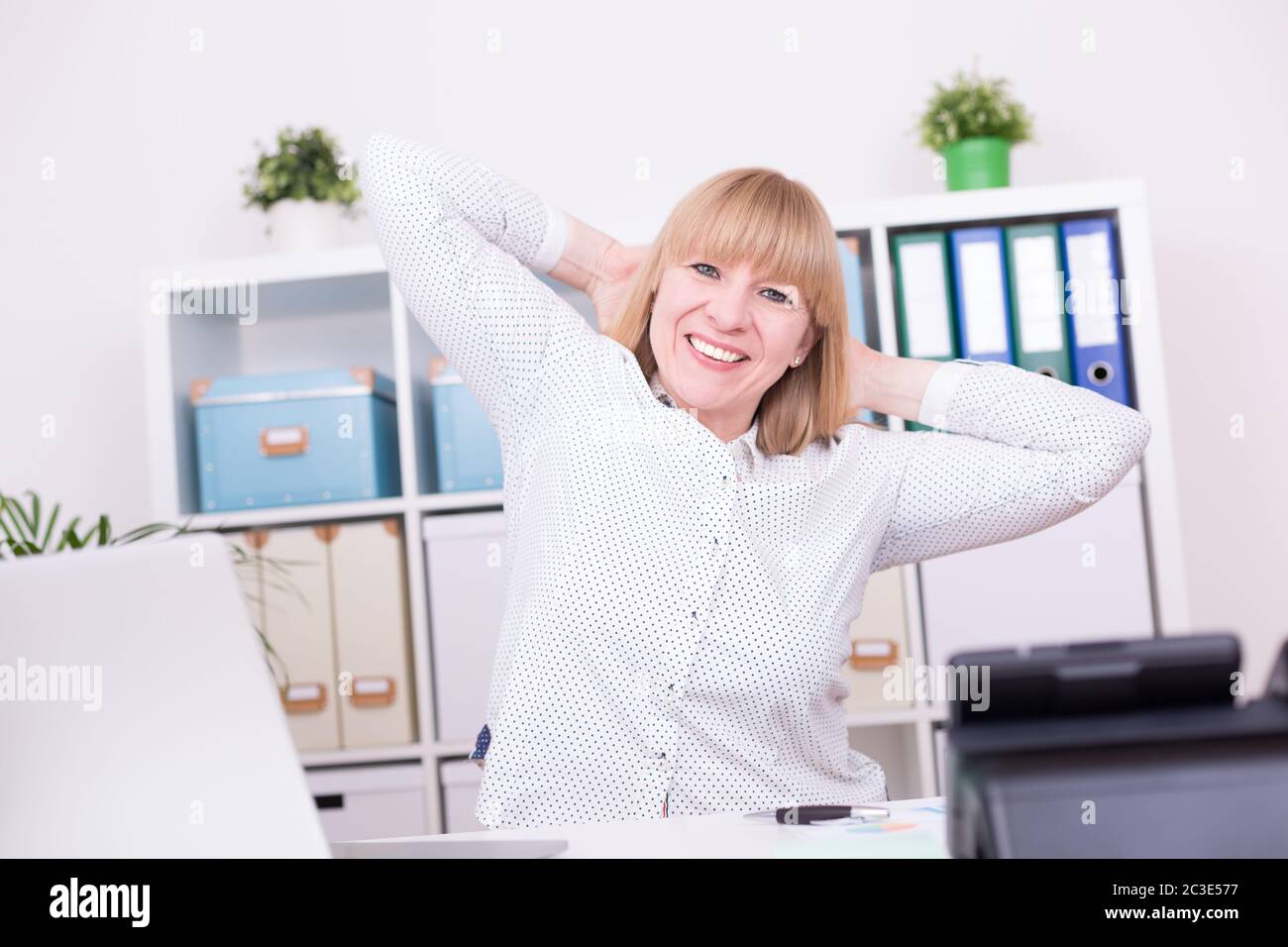 Geschäftsfrau, die im Home Office arbeitet und ihre Arme hinter dem Kopf ausstreckt. Arbeit, Entspannung a Stockfoto