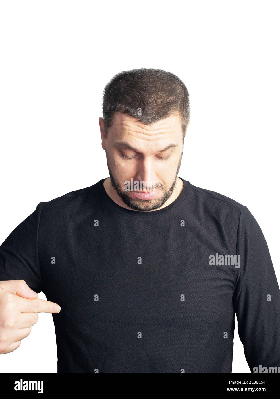 Ein bärtiger Mann in einem schwarzen Pullover schaut nach unten und zeigt mit dem Finger auf einen weißen Hintergrund Stockfoto