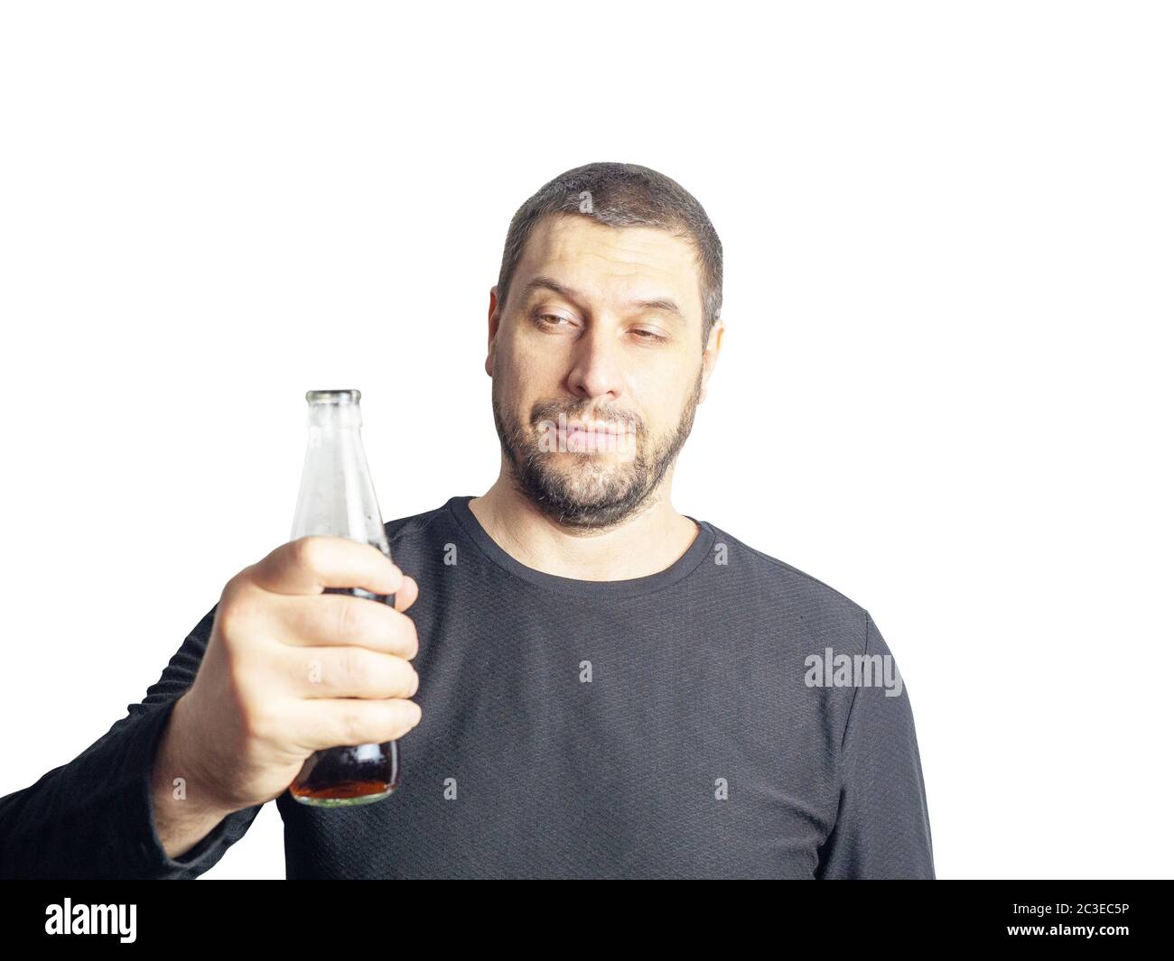 Ein dunkelhaariger Mann mit einem Bart in schwarzer Kleidung hält eine Flasche mit einem Getränk Stockfoto