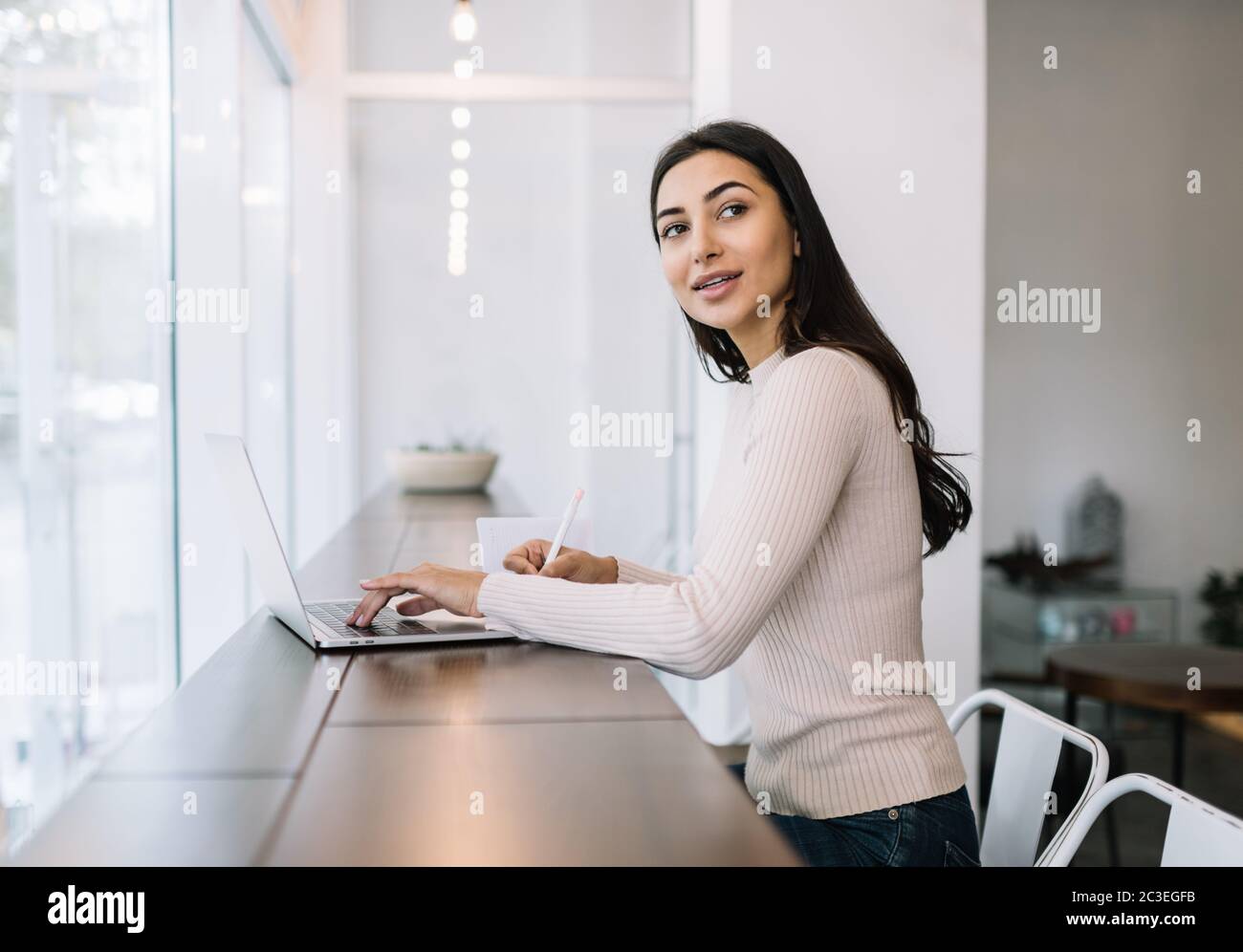 Attraktive indische Frau mit Laptop-Computer, Notizen schreiben, tippen auf der Tastatur, arbeiten von zu Hause aus. Student Lern Sprache, Prüfungsvorbereitung Stockfoto