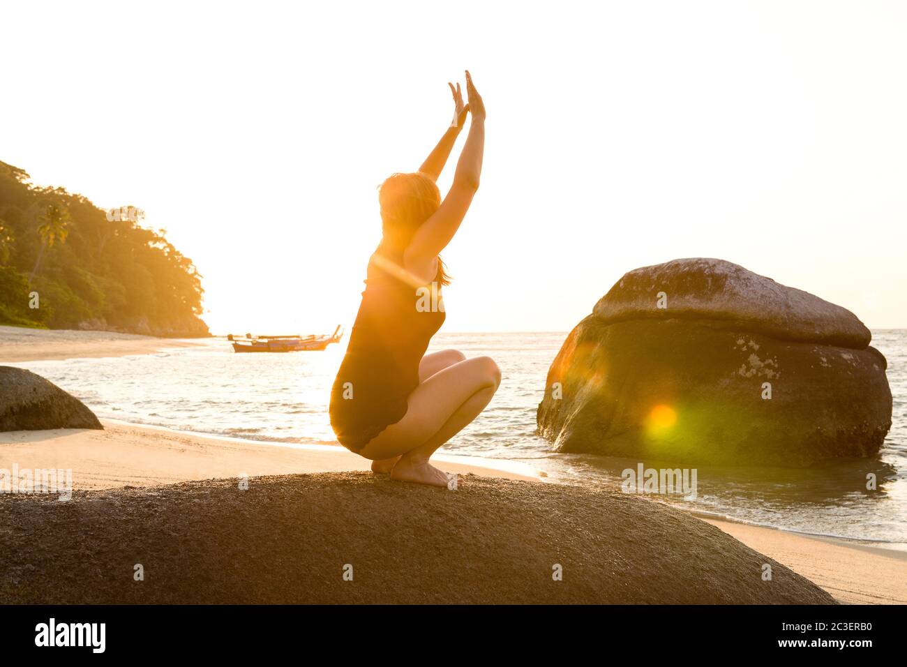 Schöne Frau, die Yoga-Übungen am tropischen Strand bei Sonnenaufgang macht. Stockfoto