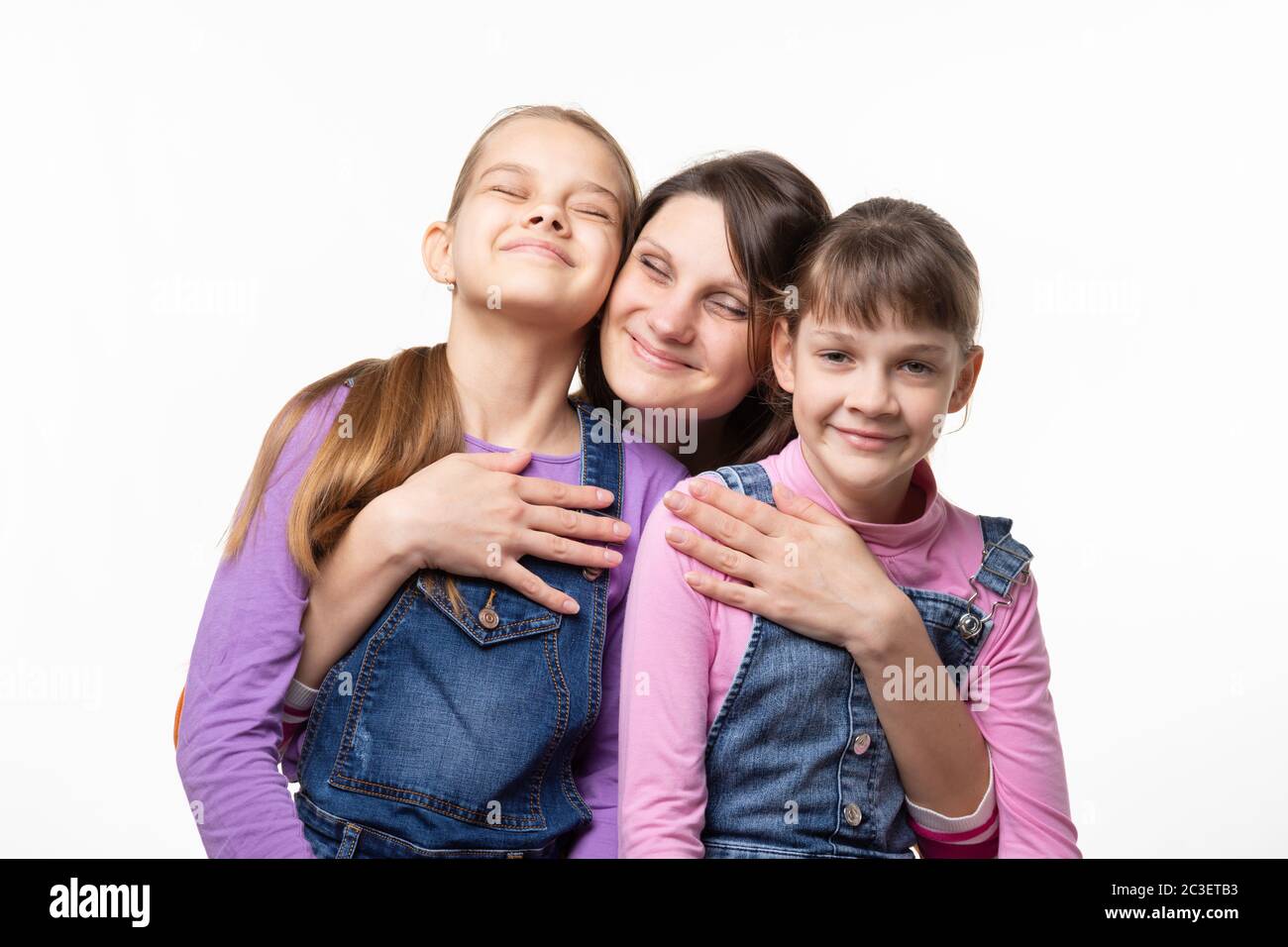 Mama klammerte sich glücklich an ihre Töchter, isoliert auf weißem Hintergrund Stockfoto