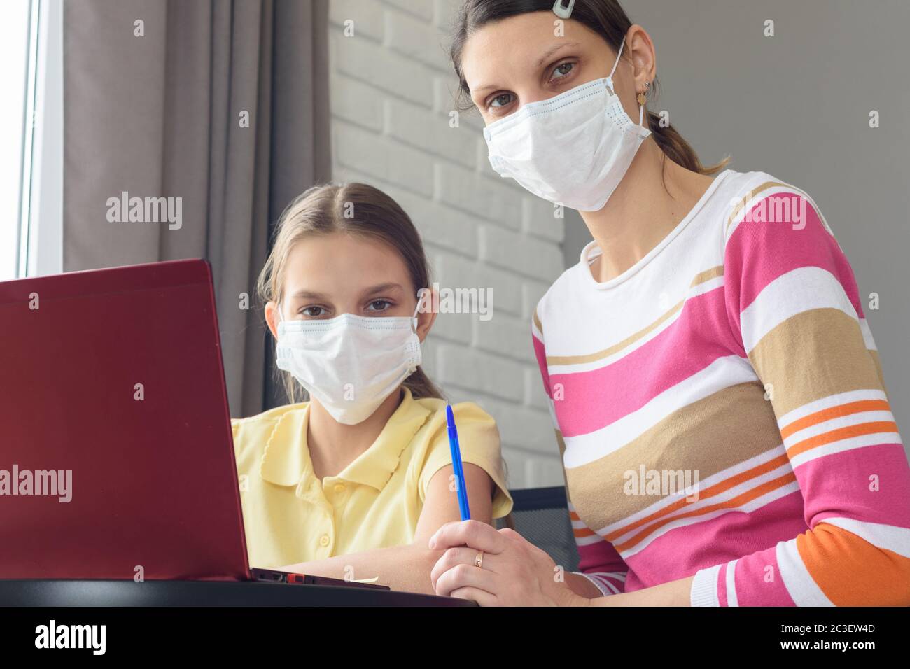 Mutter und Tochter in medizinischen Masken haben online eine Studie unter Quarantäne gestellt Stockfoto Mutter und Tochter in medizinischen Masken haben online eine Studie unter Quarantäne gestellt Stockfoto