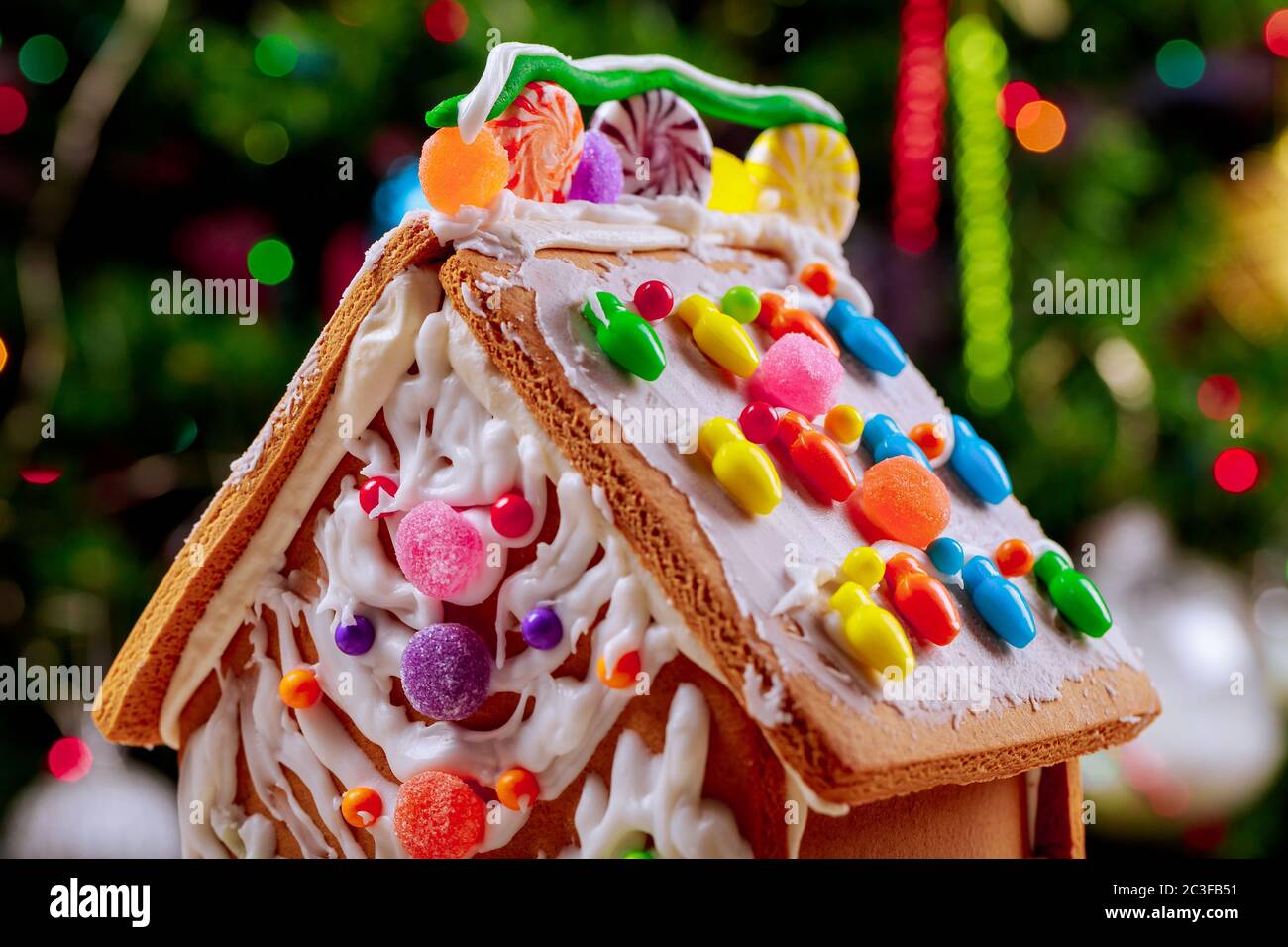 Dekoriertes Lebkuchenhaus mit Süßigkeiten auf weihnachtsbaum Lichter Hintergrund. Stockfoto