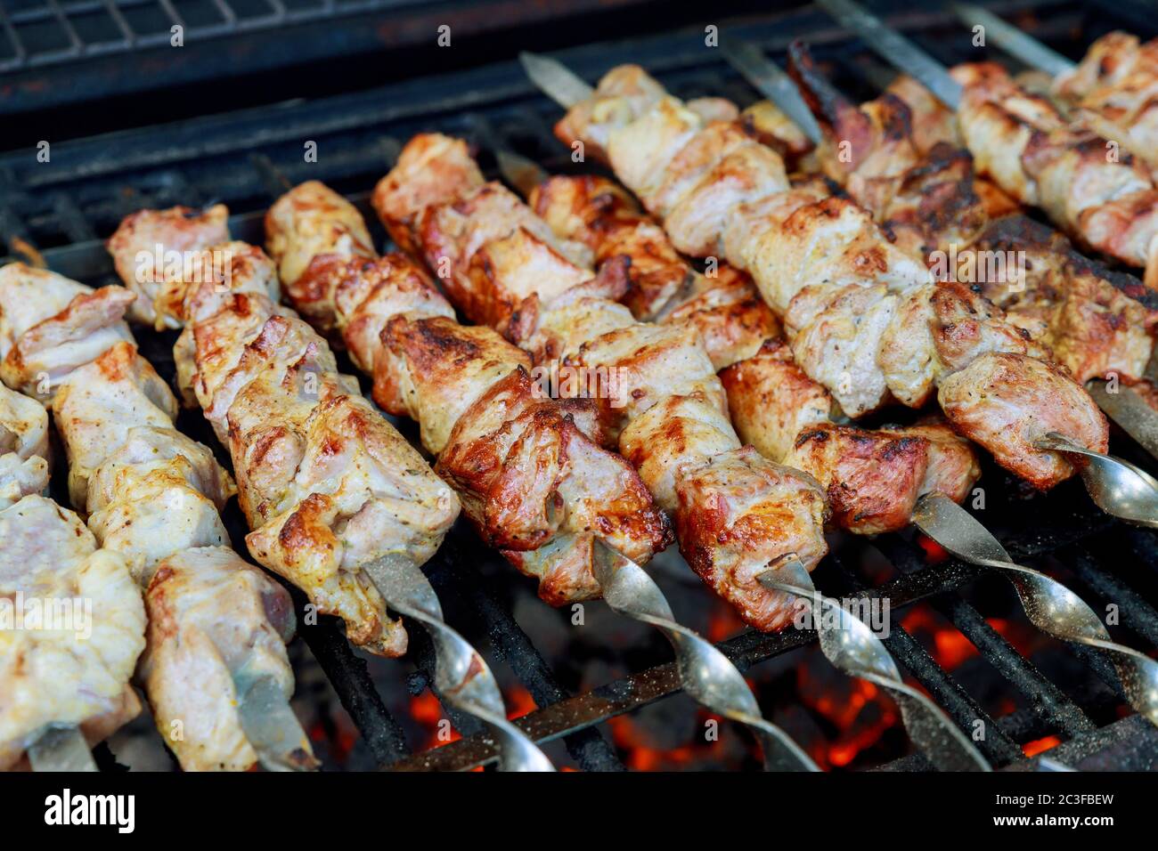 Fleisch auf Metallspieße wird mit brennender Holzkohle gegrillt. Stockfoto
