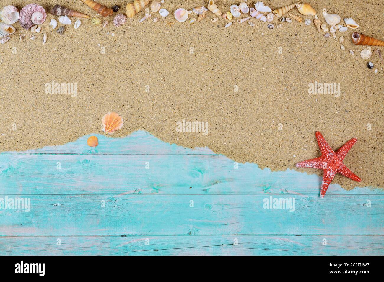 Roter Seesterne mit Muscheln auf Meersand auf blauem Holzhintergrund. Sommer- oder Urlaubskonzept. Stockfoto