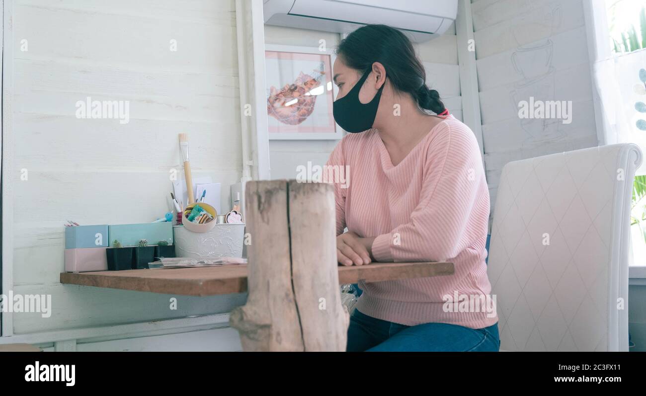 Die Kauffrau saß im Laden und wartete auf den Kunden. Vom Ausbruch des Corona-Virus betroffene Stores (COVID-19). Stockfoto