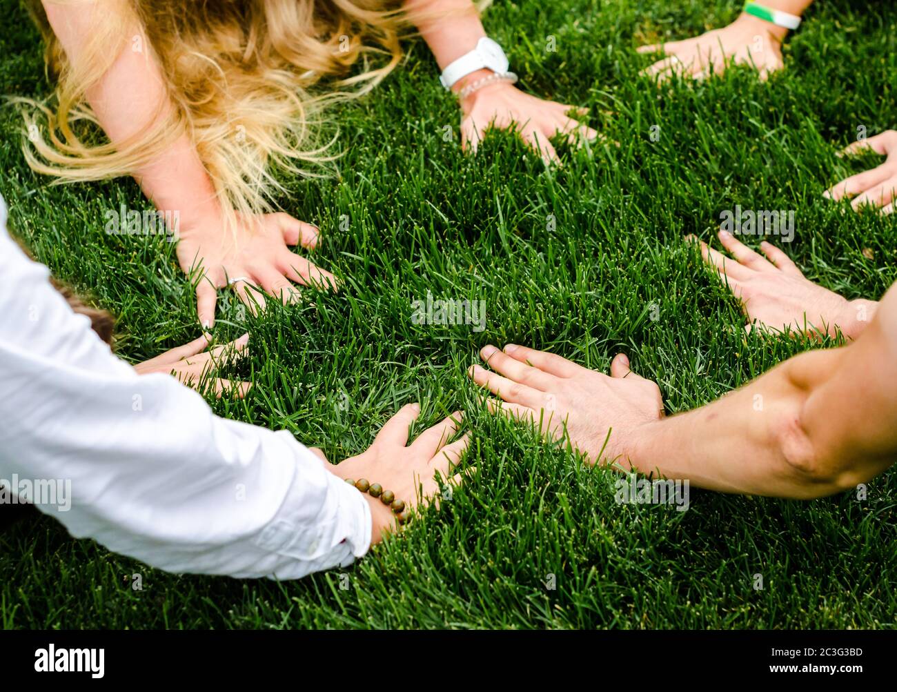 Hände der Menschen nebeneinander auf grünem Gras Stockfoto