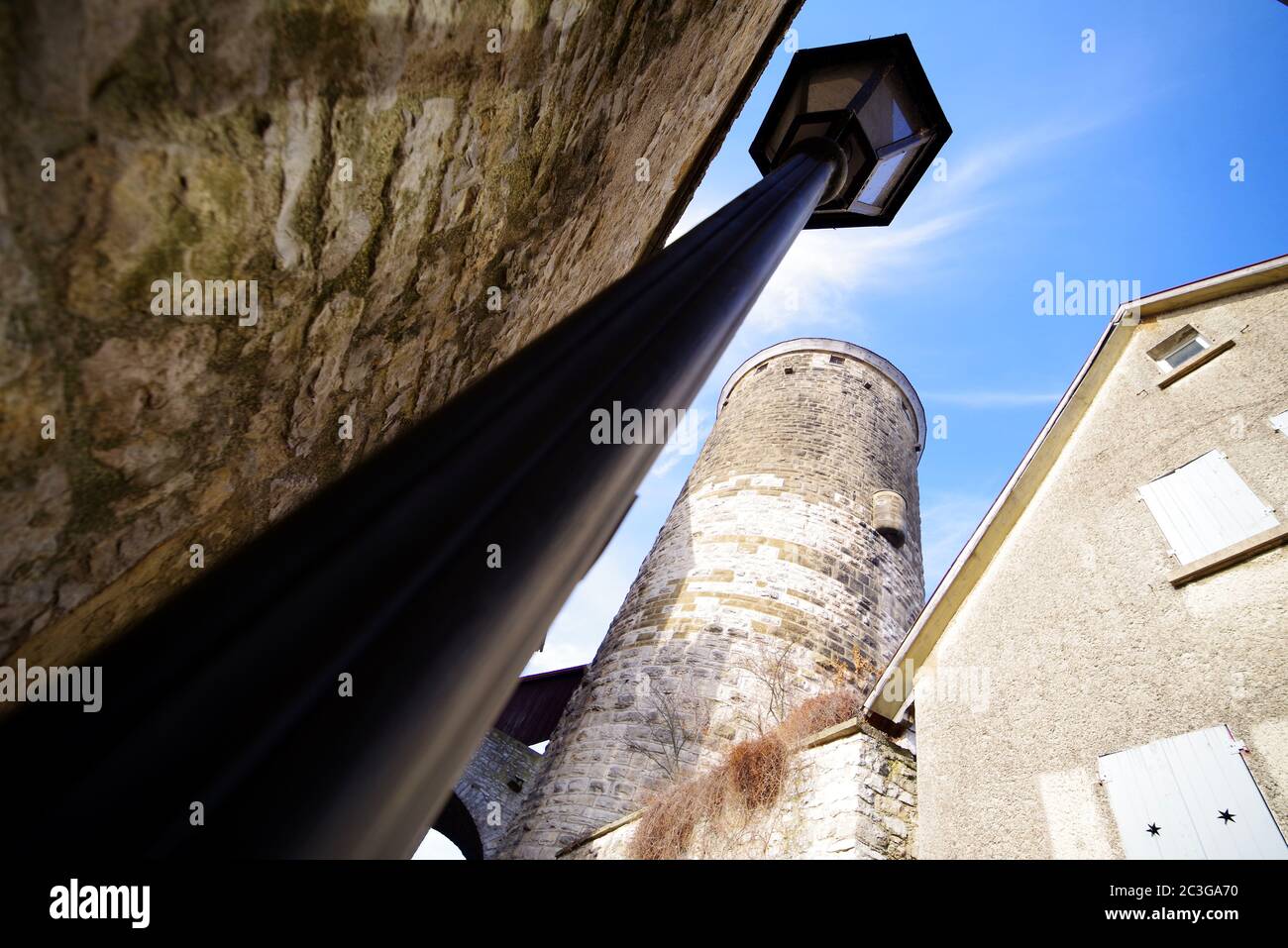 Mittelalterlicher Wachturm mit Straßenlampe unter blauem Himmel in Weitwinkeloptik Stockfoto