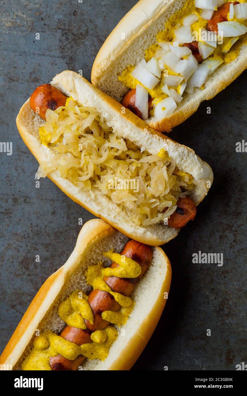 Drei Hotdogs mit Senf, Sauerkraut und Zwiebeln Stockfoto