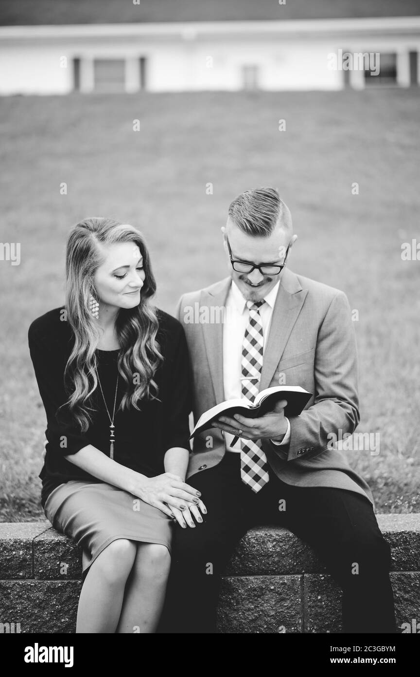 Graustufen eines Paares in einem Garten sitzen und liebevoll Gemeinsam ein Buch lesen Stockfoto