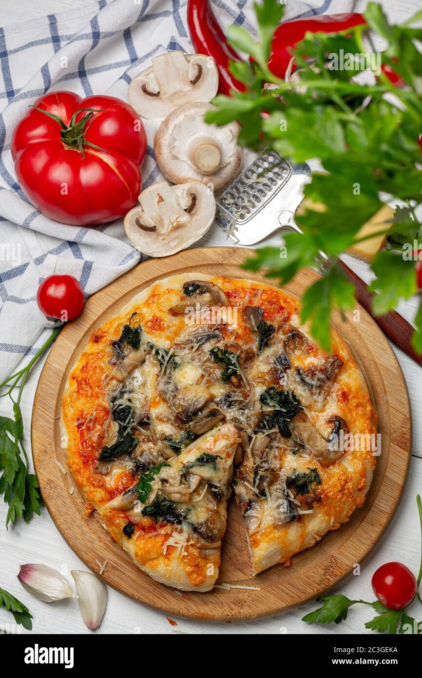 Hausgemachte Pizza mit Tomaten, Spinat und Pilzen. Stockfoto