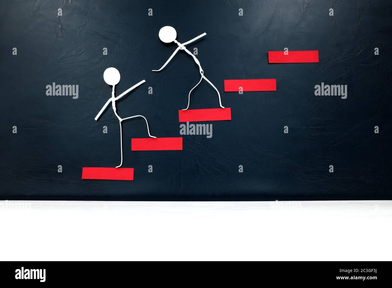 Helfende Hand, Unterstützung und Teamwork Konzept. Zwei menschliche Stockfiguren, die eine rote Leiter klettern. Stockfoto