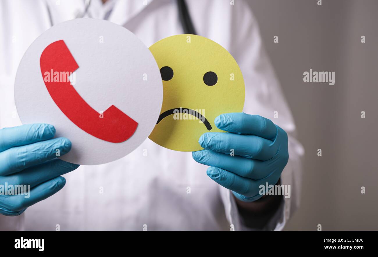 Papercuts eines Telefonsignals und traurige Emoji in der Die Hände des Arztes mit den medizinischen Handschuhen Stockfoto