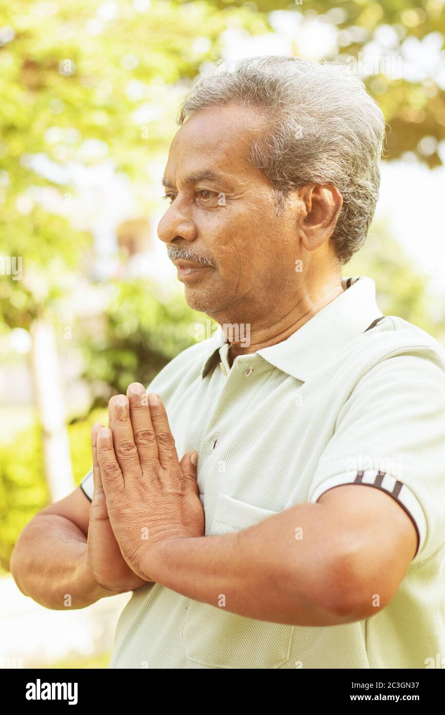 Yoga im Park. Senior man in namaste Pose - ältere 60s Menschen Fitness, Yoga und gesunde Lebensweise Konzept. Stockfoto