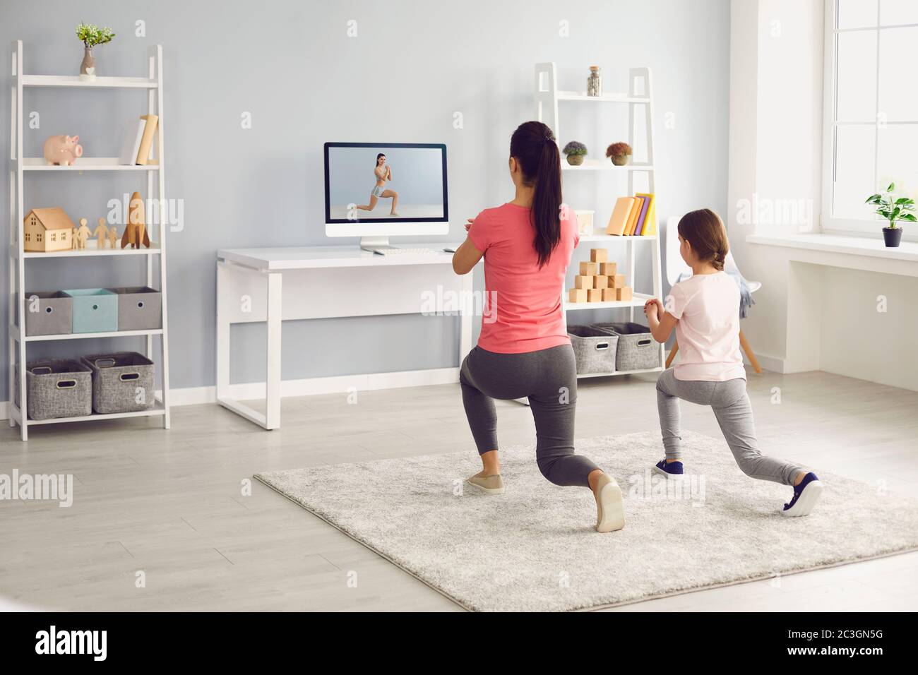 Familie macht Übungen online. Mutter und Tochter online Fitness-Trainer Video-Kurs im Zimmer zu Hause. Stockfoto