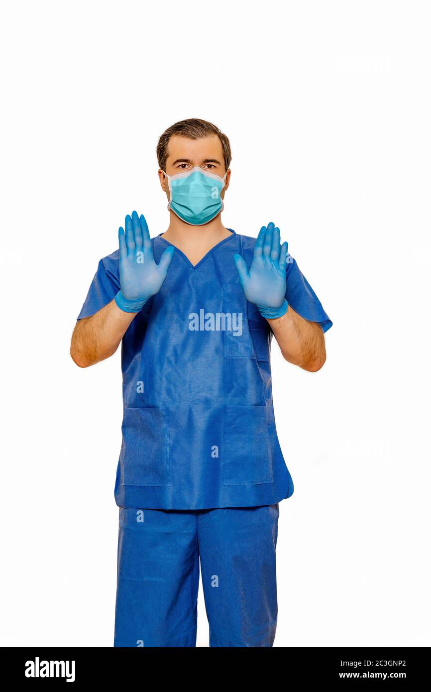 Männliche Arzt in Scrubs mit Schutzmaske und Handschuhe, die Stop-Zeichen mit beiden Händen Stockfoto