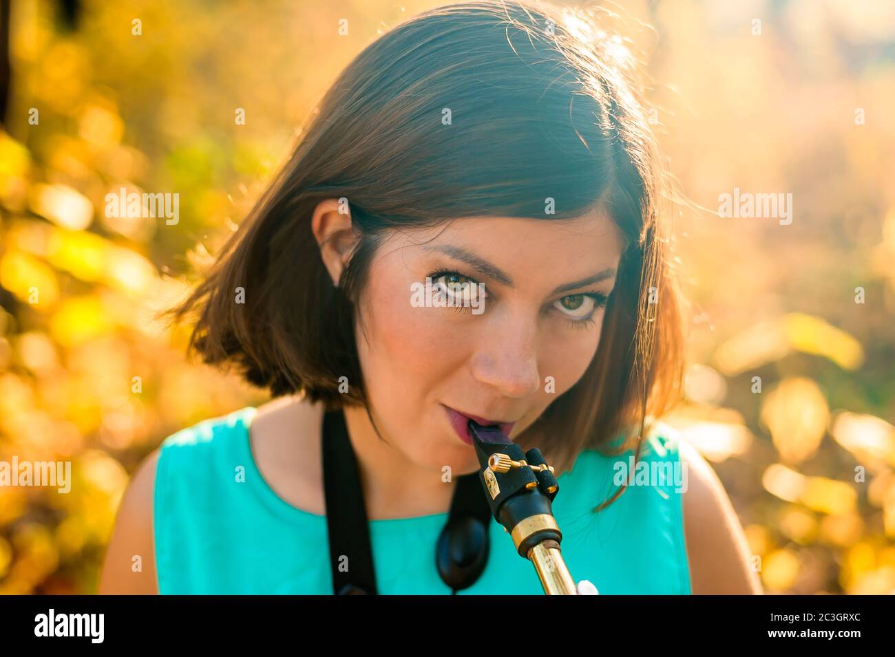Porträt einer niedlichen jungen Saxophonistin mit schwarzen Haaren in blauer Kleidung auf gelbem Hintergrund Stockfoto