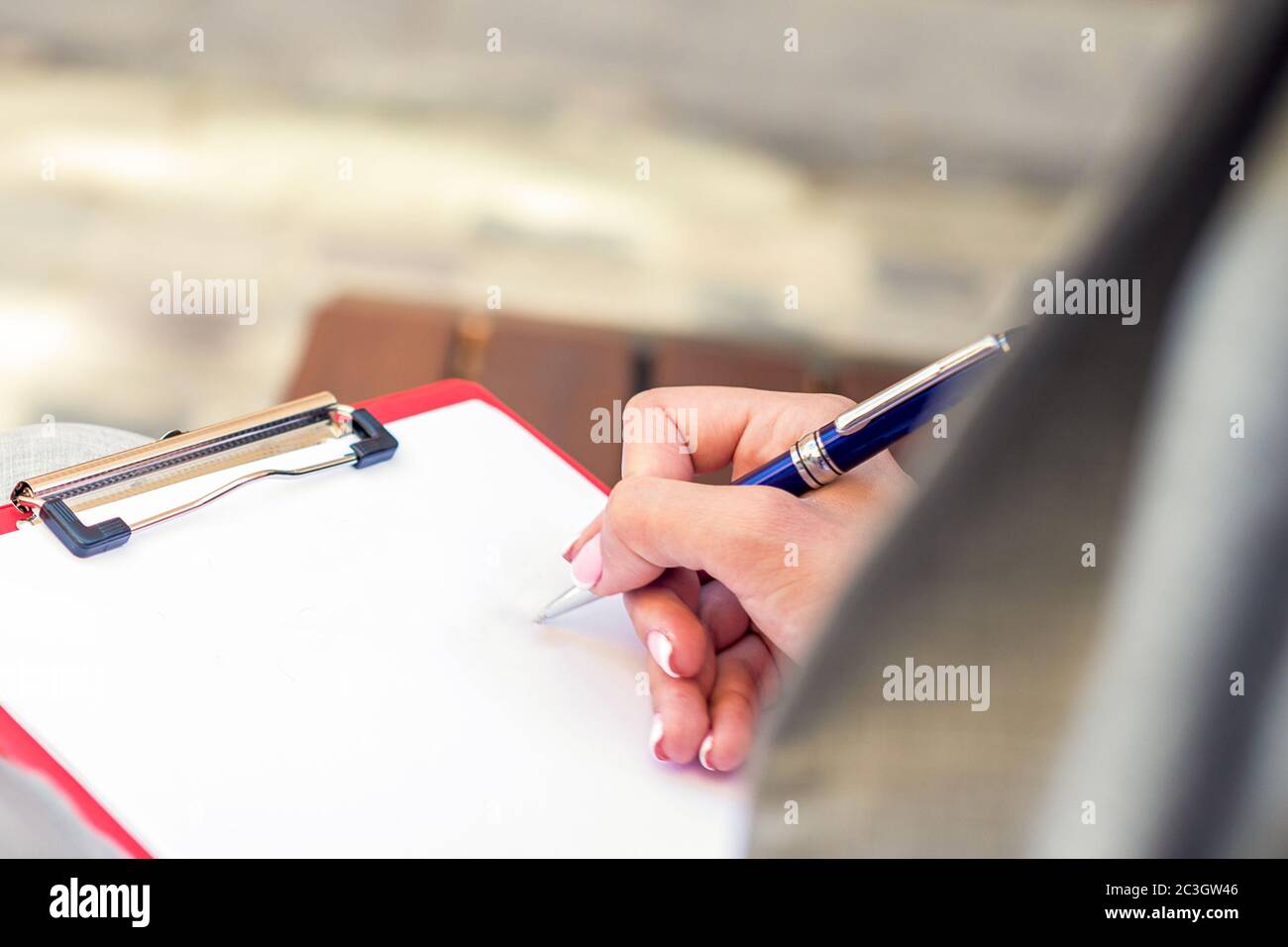 Nahaufnahme der linken Hand der Frau, die in einem leeren Papier durch Stift draußen schreibt. Stockfoto