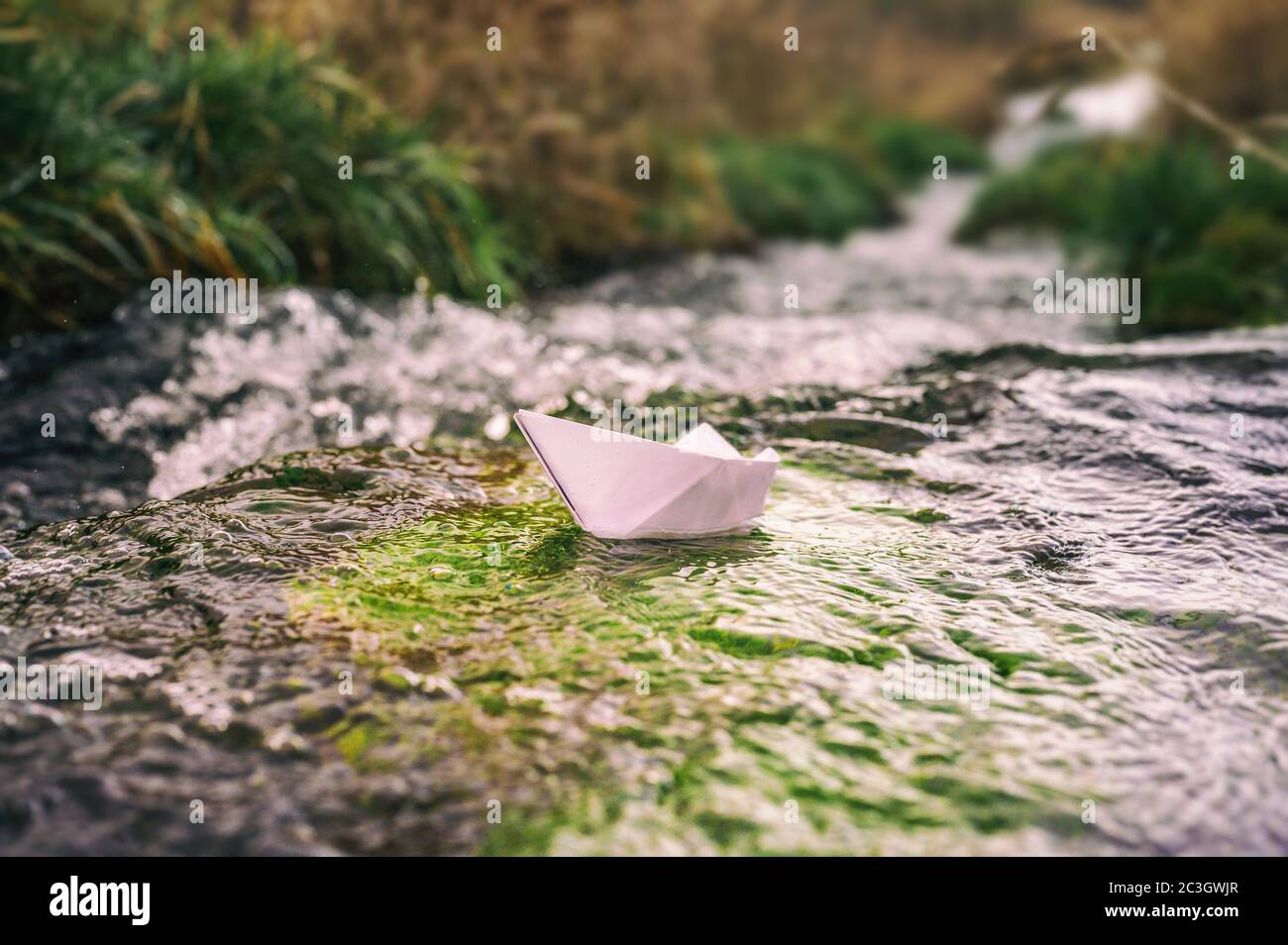 Papierboot im Bach als Metapher für Freiheit, Sehnsucht und turbulente Zeiten Stockfoto