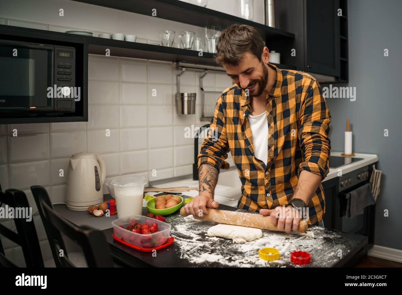 Der junge Mann macht in seiner Küche Kekse. Stockfoto