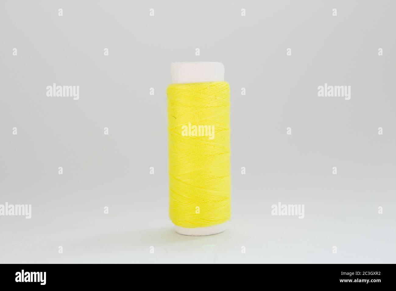 Spule aus gelbem Faden auf weißem Hintergrund Stockfoto