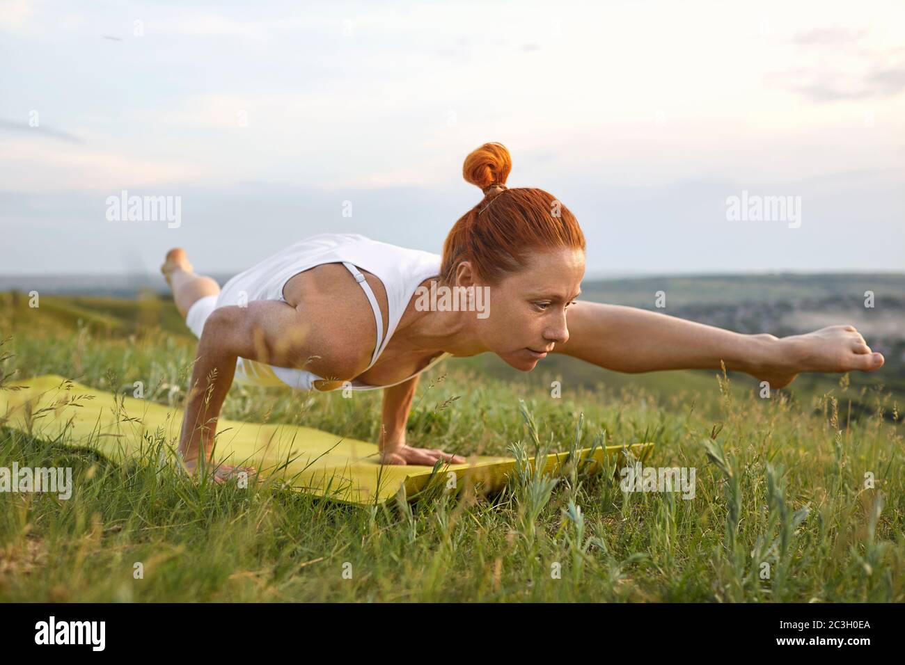 Yoga Mädchen in der Natur. Frau praktiziert Yoga Balance während sie im Sommer im Freien in einer Pose auf dem Gras auf der Natur steht. Stockfoto