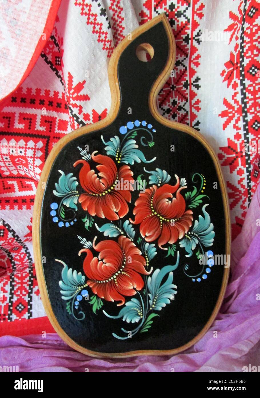 Ukrainische Volkskunst Petrikov Malerei. Dekorative Holzplatte mit roten Blumen auf dem Hintergrund der ukrainischen ruschnyk. Hochwertige Fotos Stockfoto