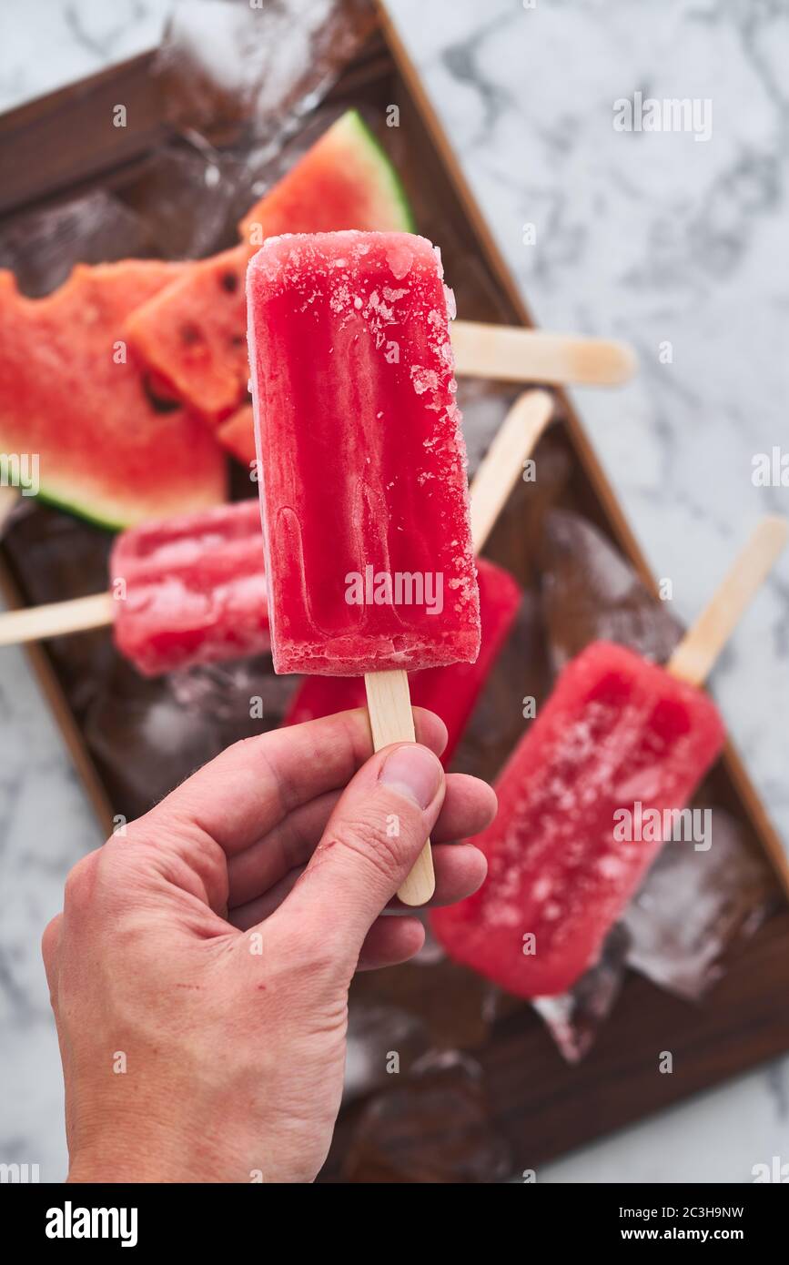 Das Servieren einer Sommerparty. Rot gefrorenes Sorbet mit dem Geschmack von Wassermelone liegt auf großen Eisstücken mit Stücken von reifen Wassermelone Stockfoto