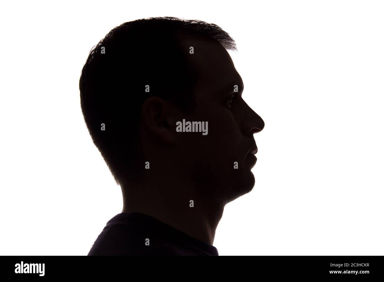 Porträt eines jungen Mannes, unrasiert, Seitenansicht - dunkel isoliert Silhouette Stockfoto