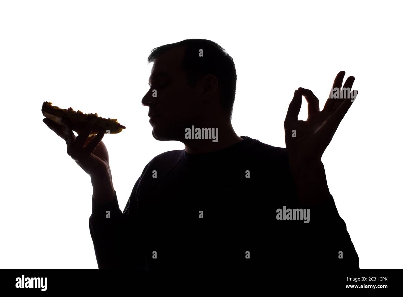 Porträt eines jungen Mannes zufrieden mit dem Geschmack von Pizza, unrasiert, Seitenansicht - dunkel isoliert Silhouette Stockfoto