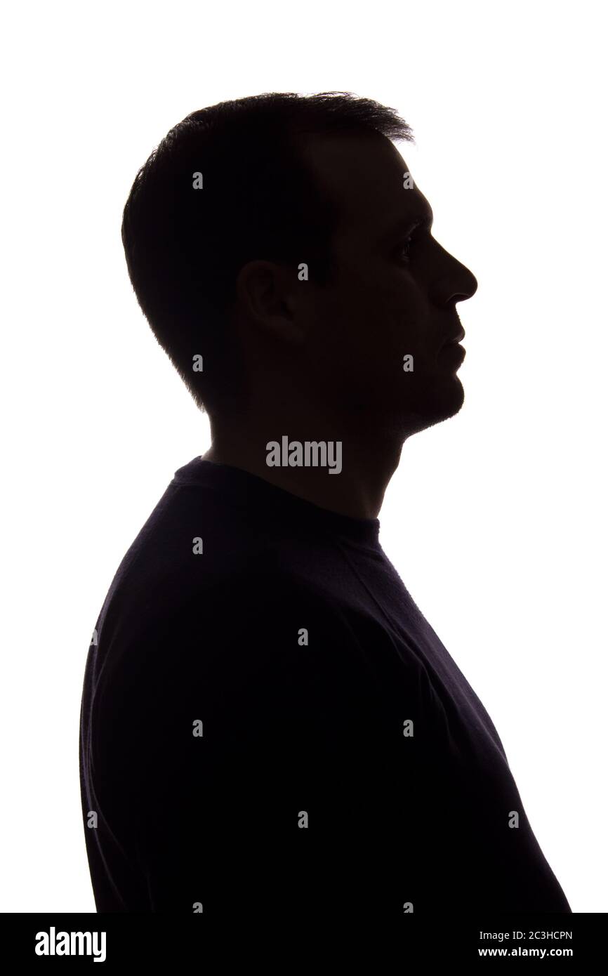 Porträt eines jungen Mannes, unrasiert, Seitenansicht - dunkel isoliert Silhouette Stockfoto