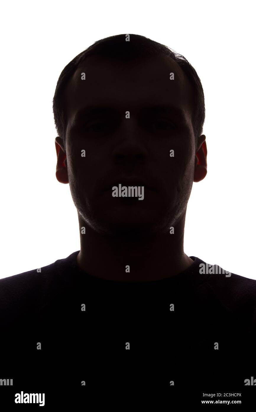 Porträt eines jungen Mannes, unrasiert, Vorderansicht - dunkel isoliert Silhouette Stockfoto