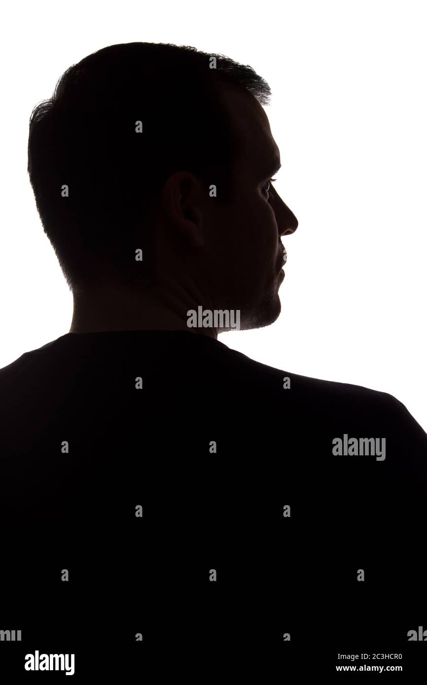 Porträt eines jungen Mannes, unrasiert, Rückansicht - dunkel isoliert Silhouette Stockfoto